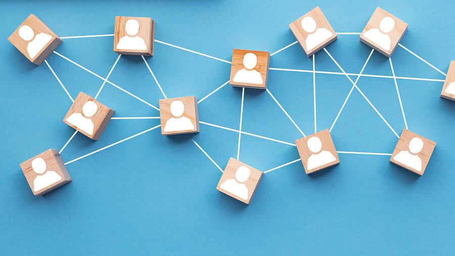 Interlinked wooden cubes with white face illustrations, representing teamwork and collaboration.