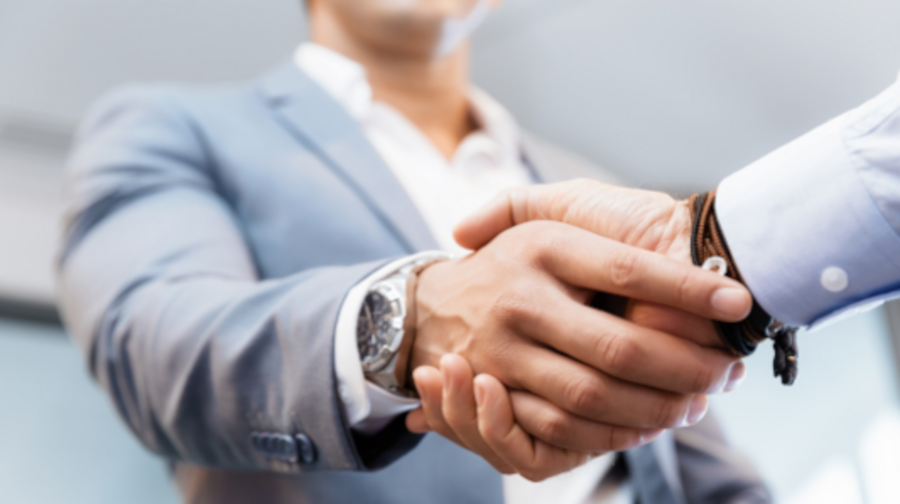 Handschlag von zwei Geschäftsleuten in grauem Sakko und weißem Hemd