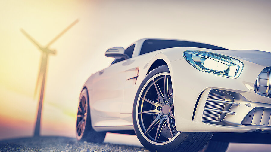 Im Vordergrund ein modernes Auto, im Hintergrund ein Windrad