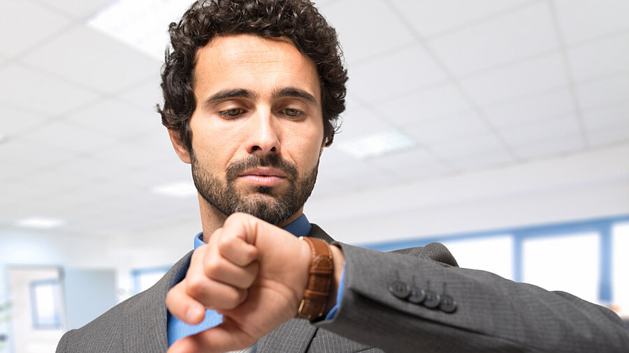 Ein Mann, der auf seine Armbanduhr schaut