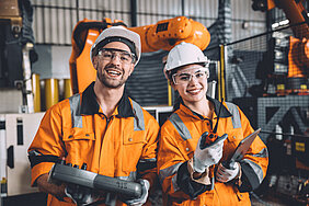 Ein Mann und einen Frau in Arbeitskleidung in einem Produktionsumfeld
